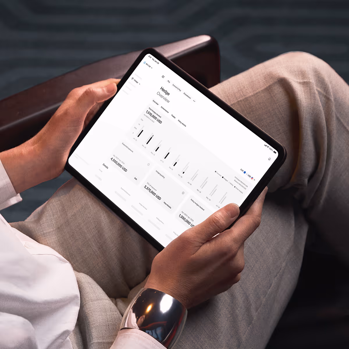 Person holding a tablet displaying financial data and charts under the heading 'Hedge Overview'.